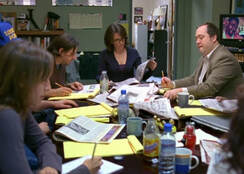 four people sitting at conference table in a meeting with note pages strewn over the table